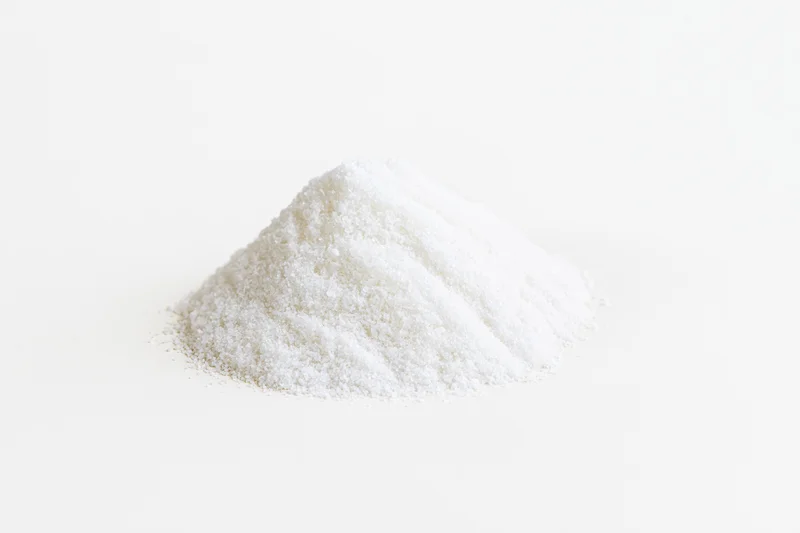 Small mound of fine white salt granules on a plain white surface
