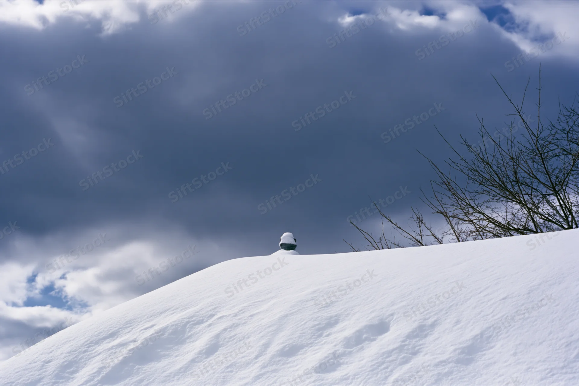 Snow-covered chimney pot on a snowdrifted roof under cloudy sky