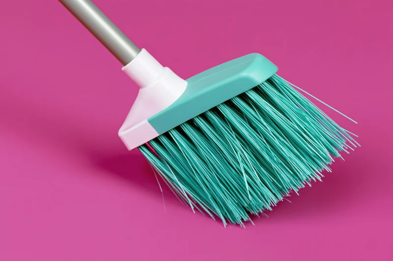 Teal plastic broom with fine synthetic bristles on pink background