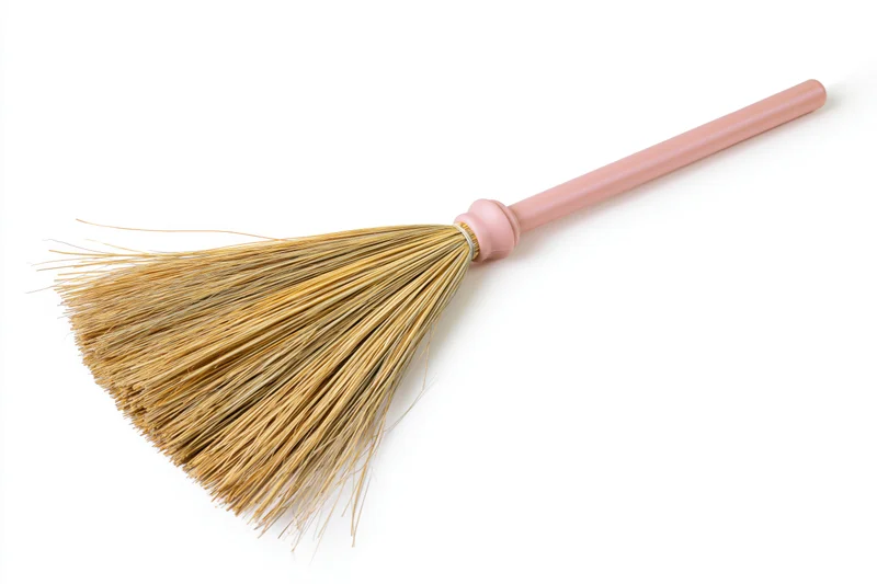 Traditional asian grass broom with pastel pink plastic handle isolated on white background