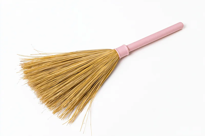 Traditional asian grass broom with pastel pink plastic handle on white background