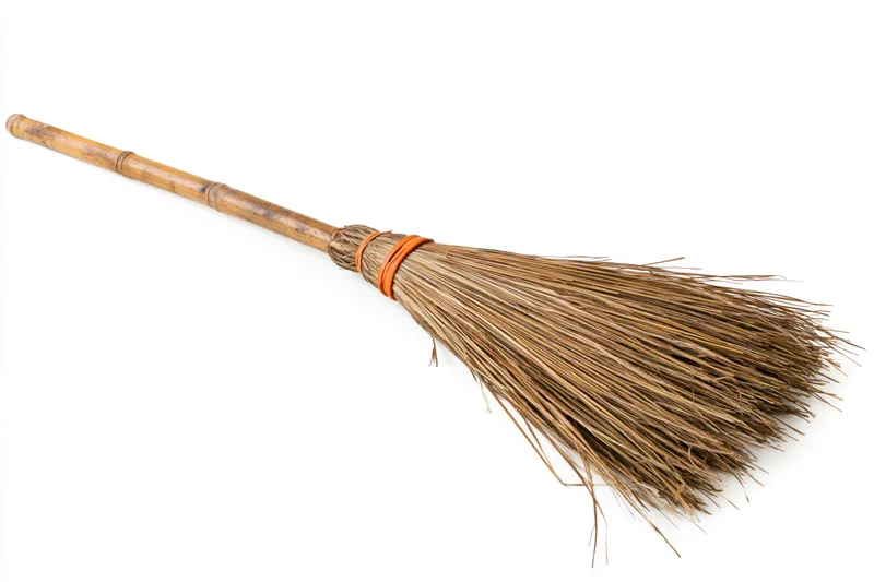 Traditional bamboo-handled broom with dried straw bristles on white background