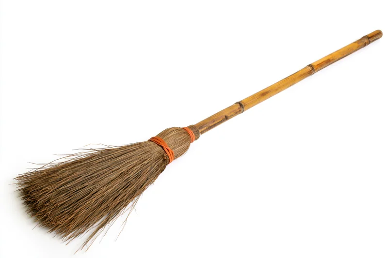 Traditional bamboo-handled broom with dried brown straw bristles on white background