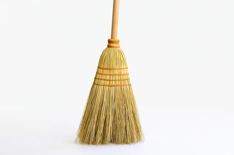 Traditional corn straw broom standing upright on white background