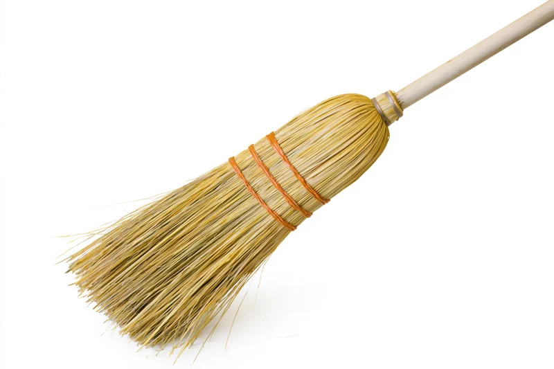 Traditional corn straw broom with wooden handle isolated on white background