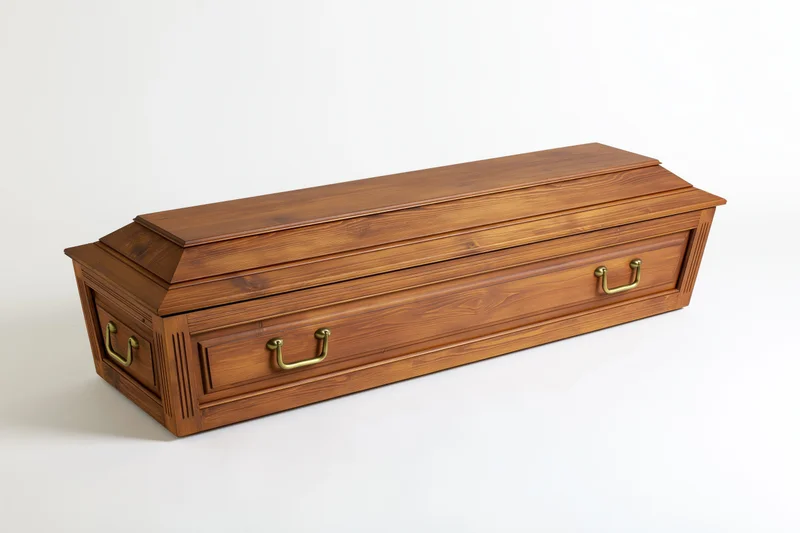 Traditional wooden coffin with brass side handles angled view on white background