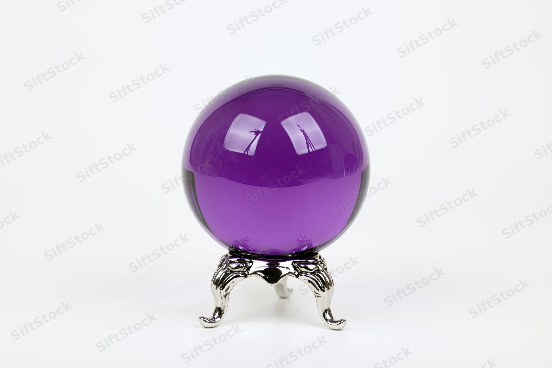Translucent purple glass crystal ball on a metallic stand against white background