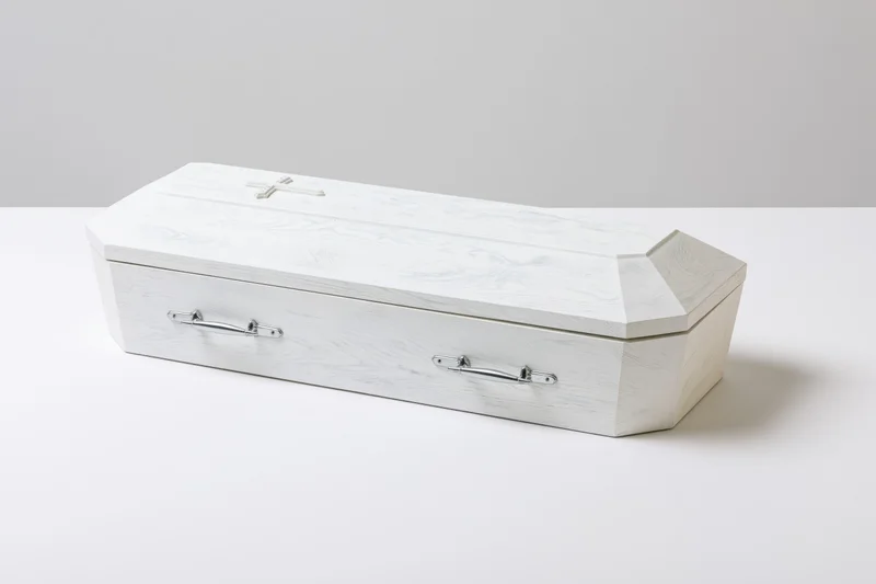 White painted wooden coffin with silver handles on a plain white surface
