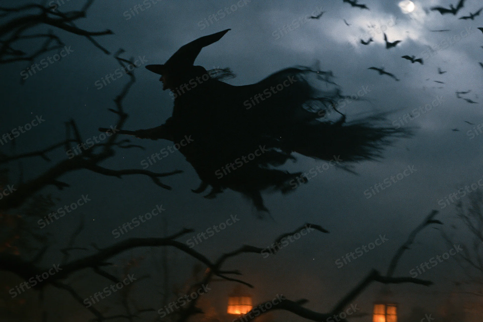 Witch silhouette flying on broomstick at night among bare trees and bats under moonlight