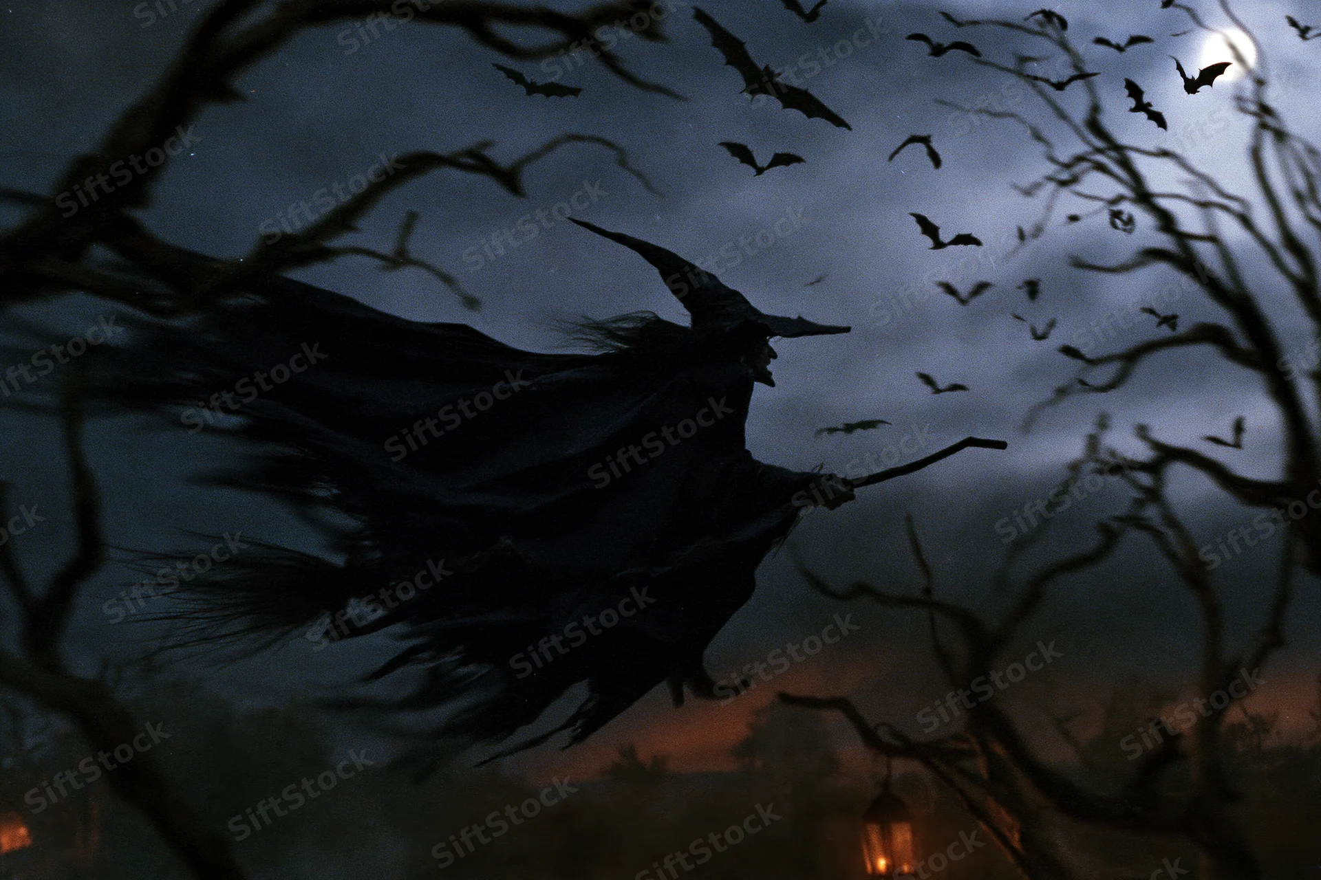 Witch flying on broomstick through moonlit night sky with bats and bare trees