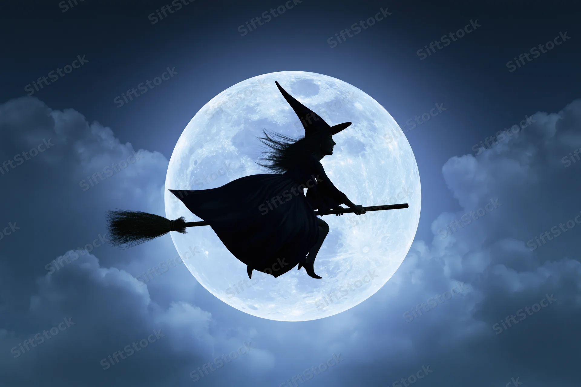 Witch silhouette flying on broomstick against full moon in cloudy night sky