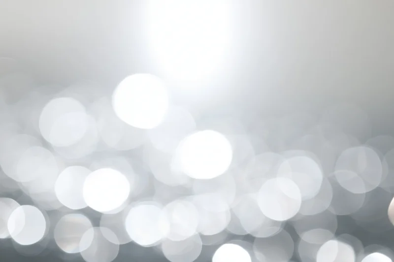 Abstract bokeh background with soft white circular lights and gradient gray tones