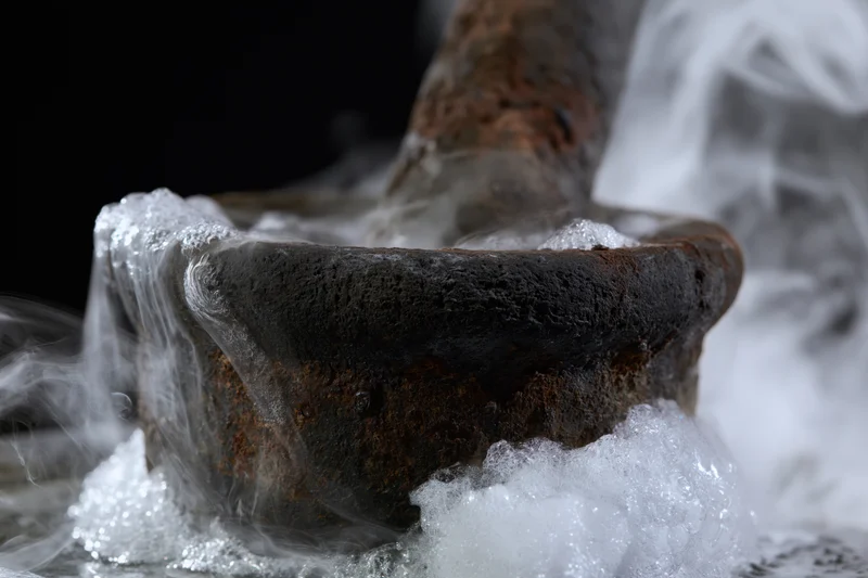 Aged rusty stone mortar and pestle surrounded by thick billowing vapor and foam