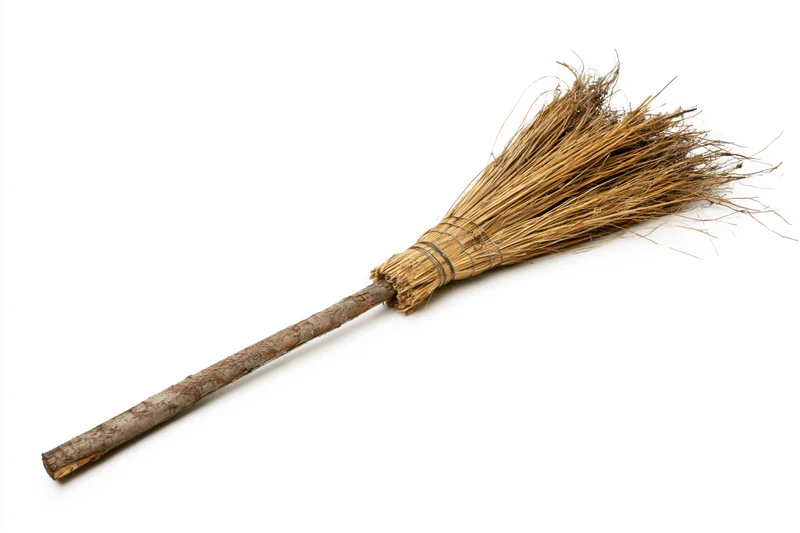 Old handmade straw broom lying diagonally on white background