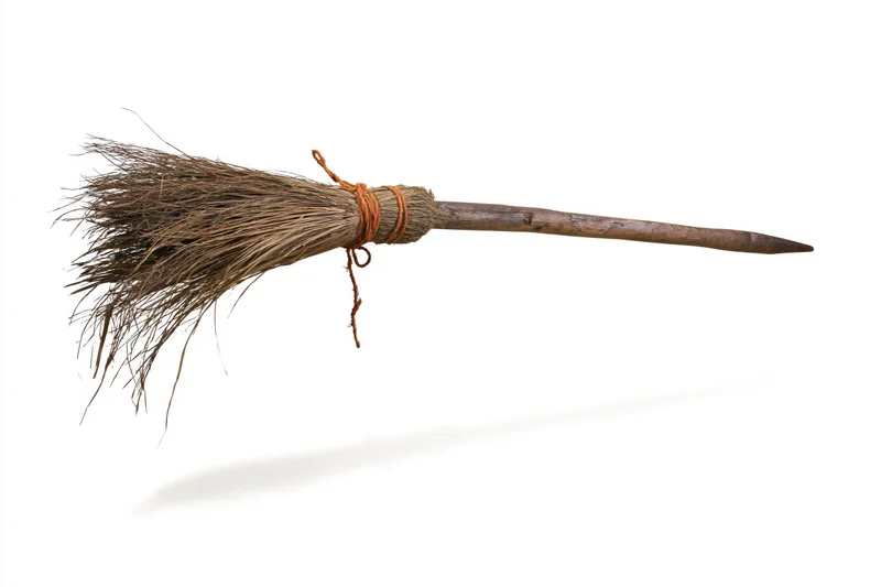 Old rustic witch's broom with dried straw bristles tied to wooden handle on white background