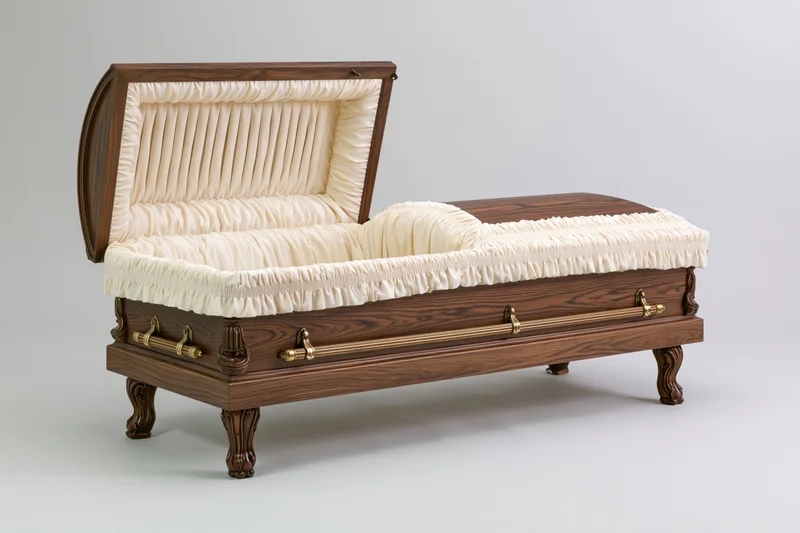 Open wooden funeral casket with raised lid revealing cream fabric interior on plain background