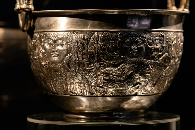 Ancient silver cauldron with embossed mythological figures on display
