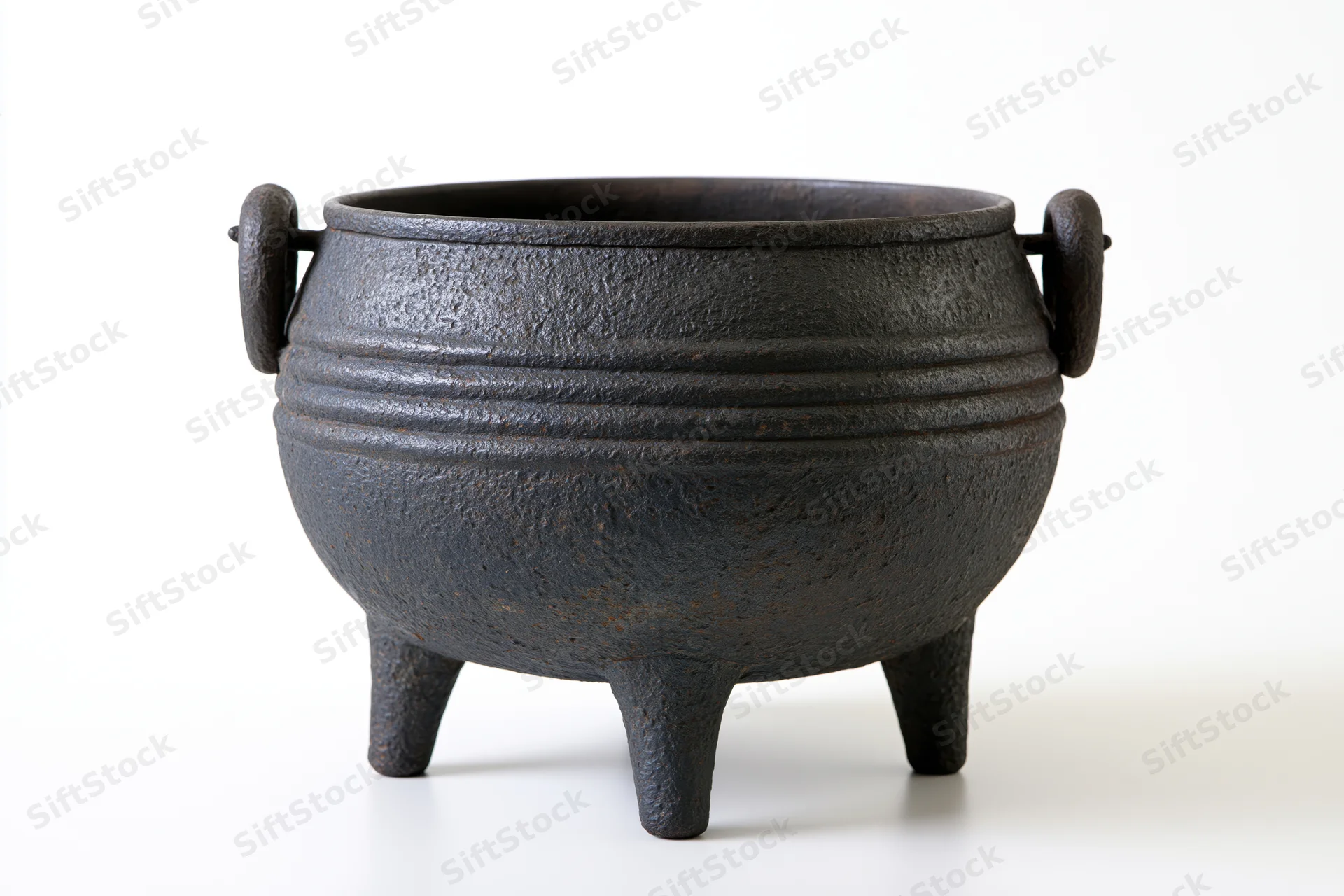 Antique cast iron cauldron with three legs and side handles on white background