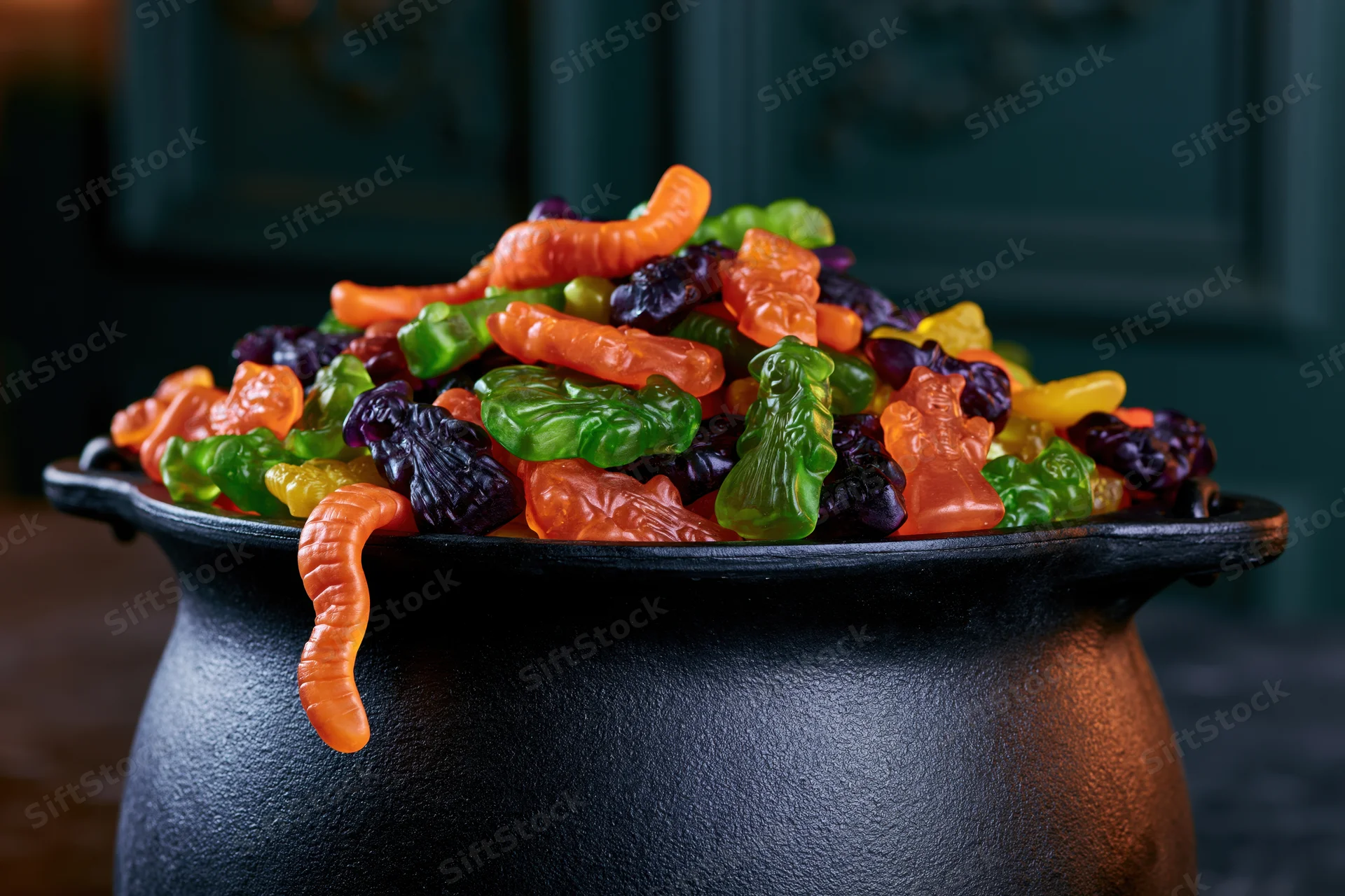 Black cast iron cauldron overflowing with colorful halloween gummy candies