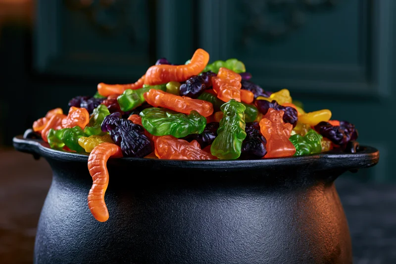 Black cast iron cauldron overflowing with colorful halloween gummy candies