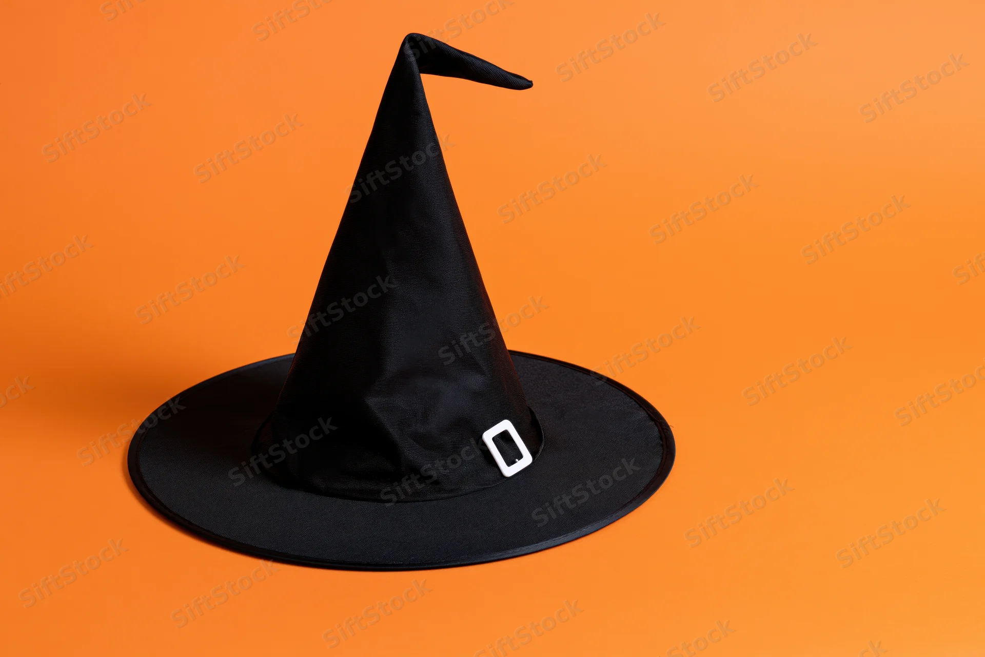 Black witch hat with white buckle on orange background