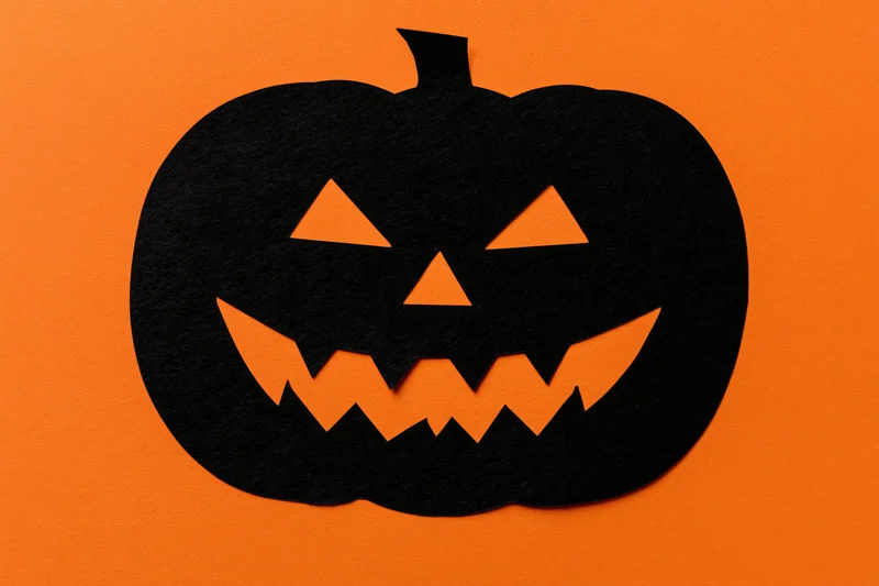 Black paper cutout jack-o-lantern face on orange background