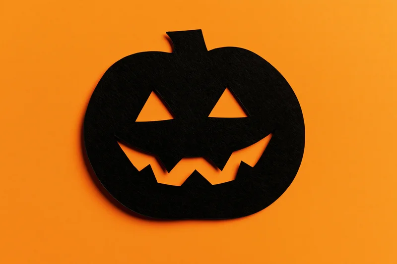 Black paper jack-o-lantern silhouette on orange background