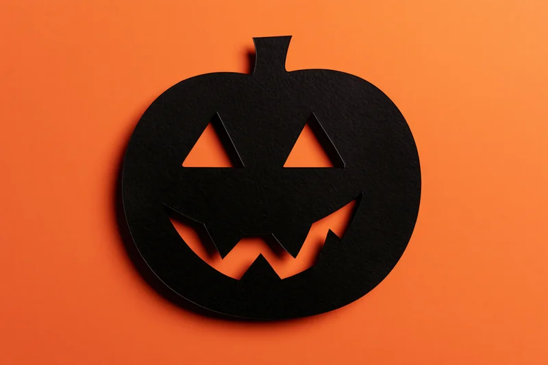 Black paper jack-o-lantern cutout on orange background