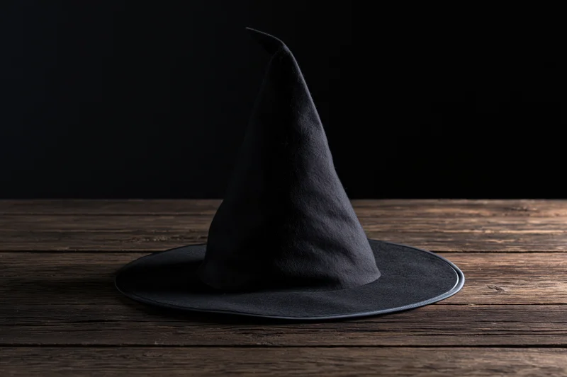 Black pointed witch hat resting on a dark weathered wooden table