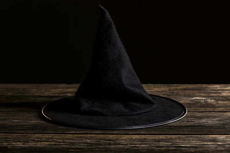 Black pointed witch hat resting on a dark weathered wooden table