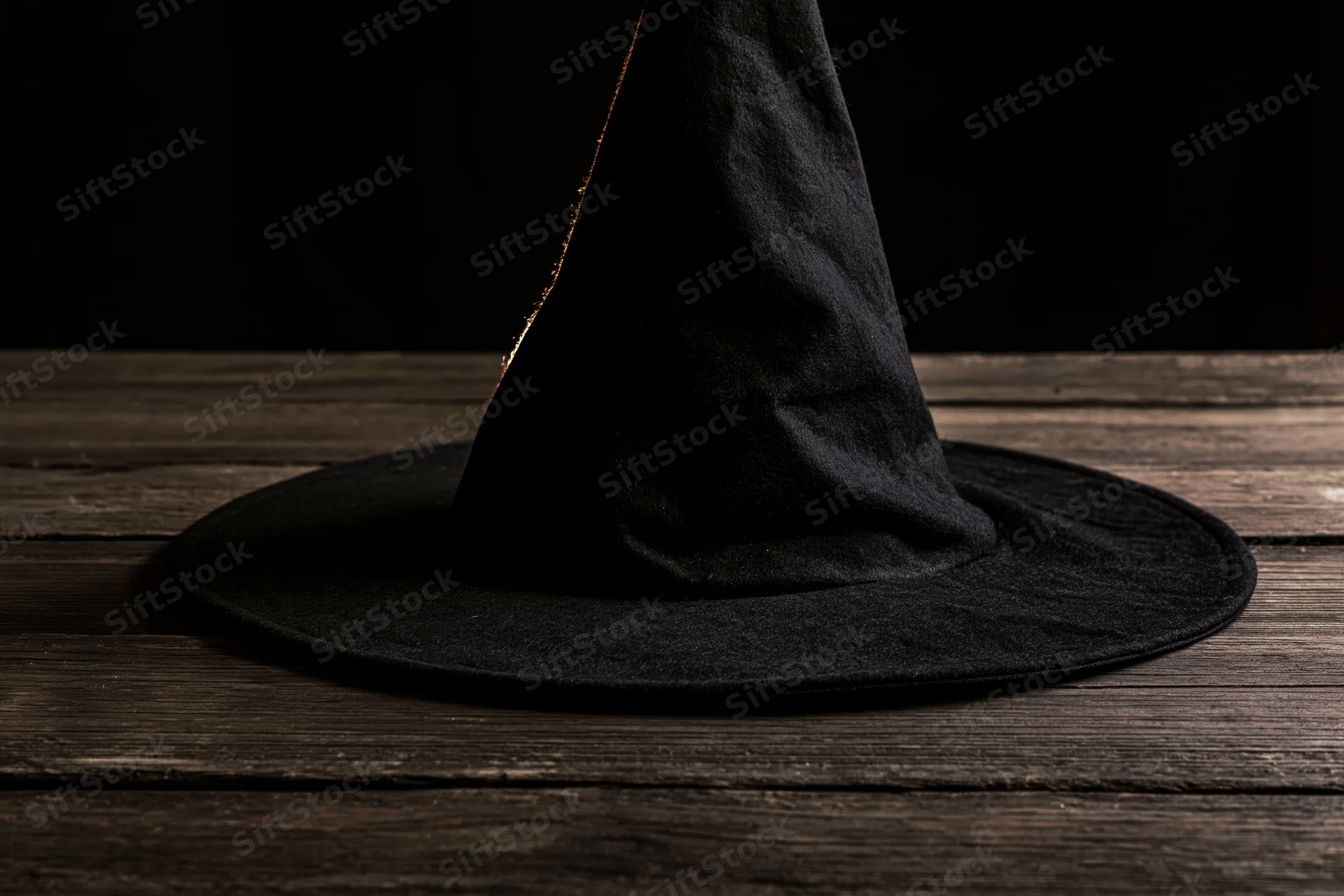 Black pointed witch hat resting on dark weathered wooden table