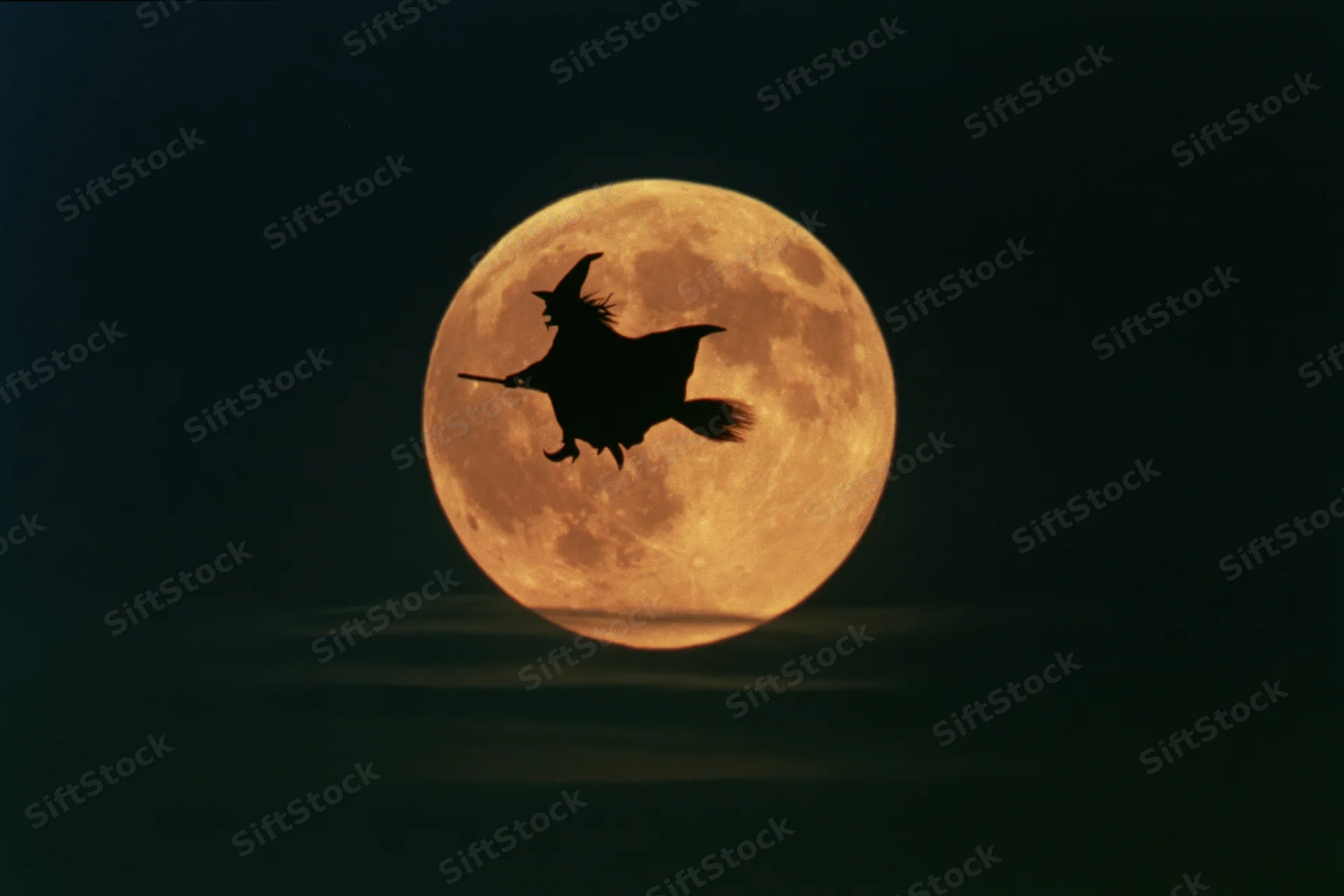 Witch flying on broomstick silhouetted against full moon at night