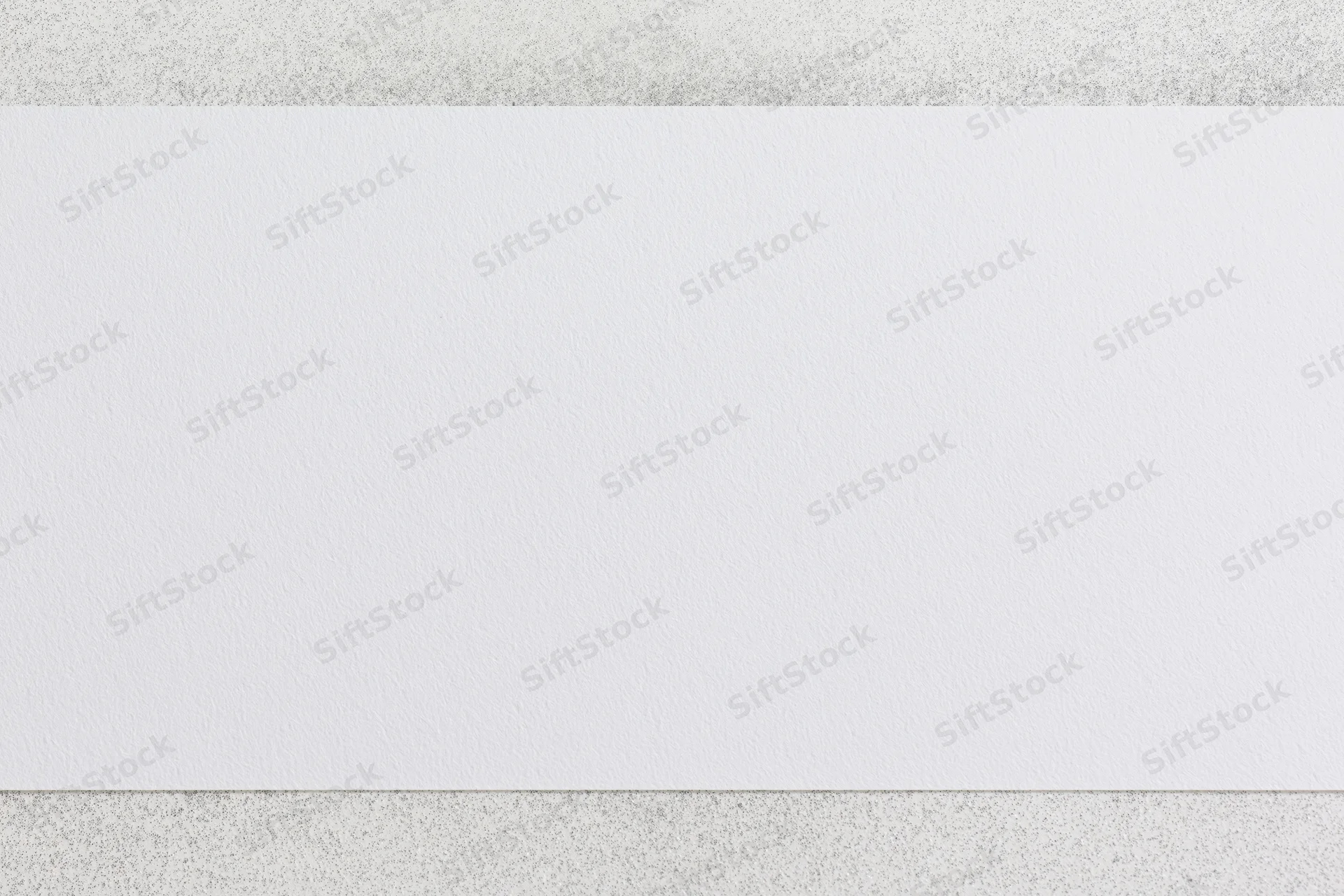 Blank white paper sheet with faint speckled texture on a neutral surface