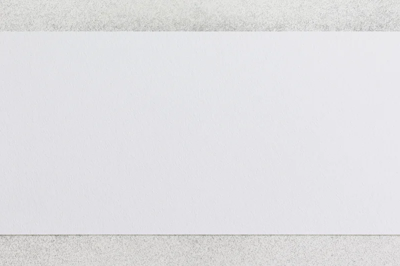Blank white paper sheet with faint speckled texture on a neutral surface