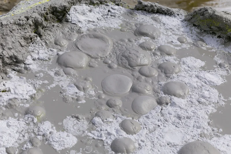 Boiling mud pool with dome-shaped blisters on a geothermal landscape
