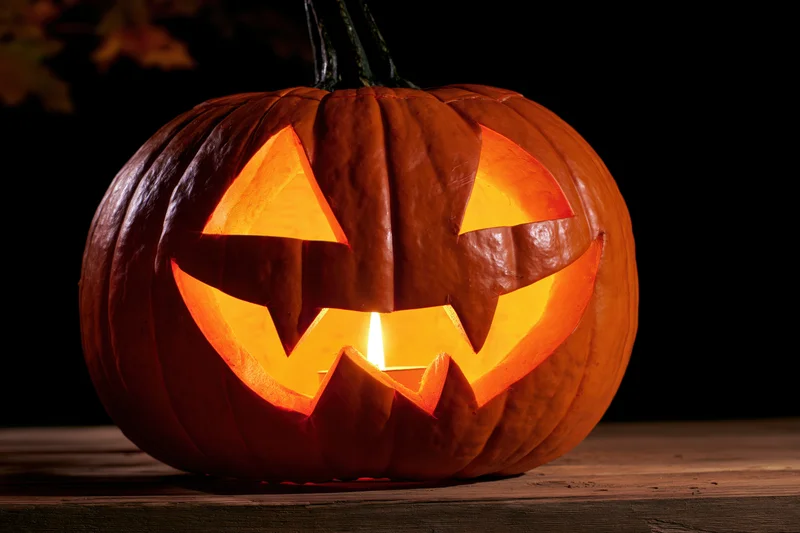 Carved pumpkin glowing from within on wooden surface