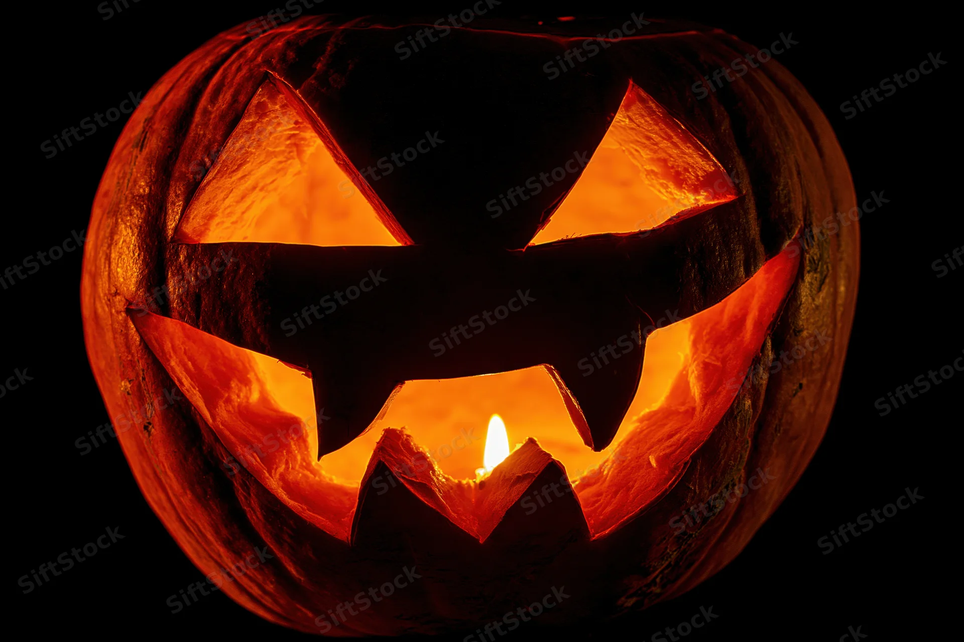 Carved pumpkin glowing with candlelight against dark background