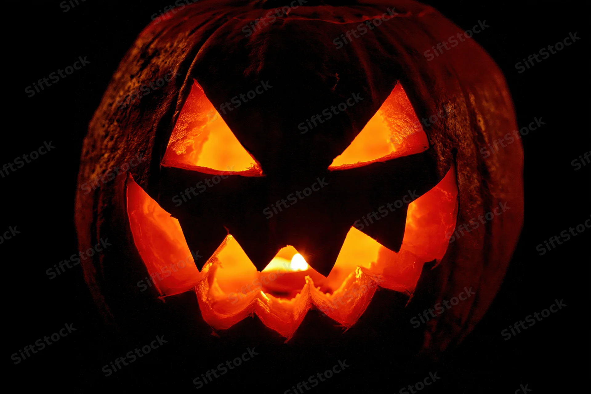 Carved pumpkin glowing with candlelight at night