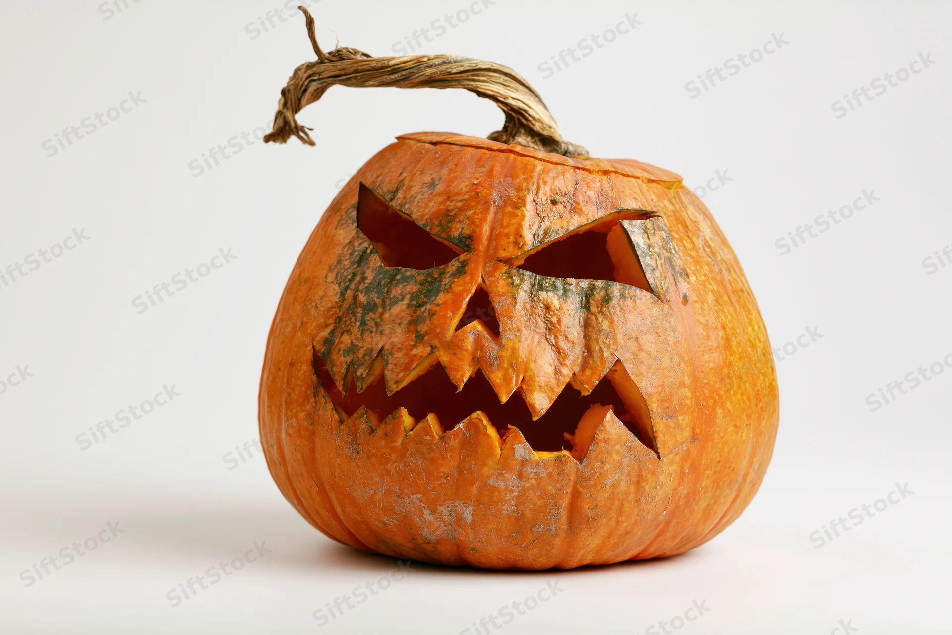 Carved pumpkin with jagged menacing face on white background