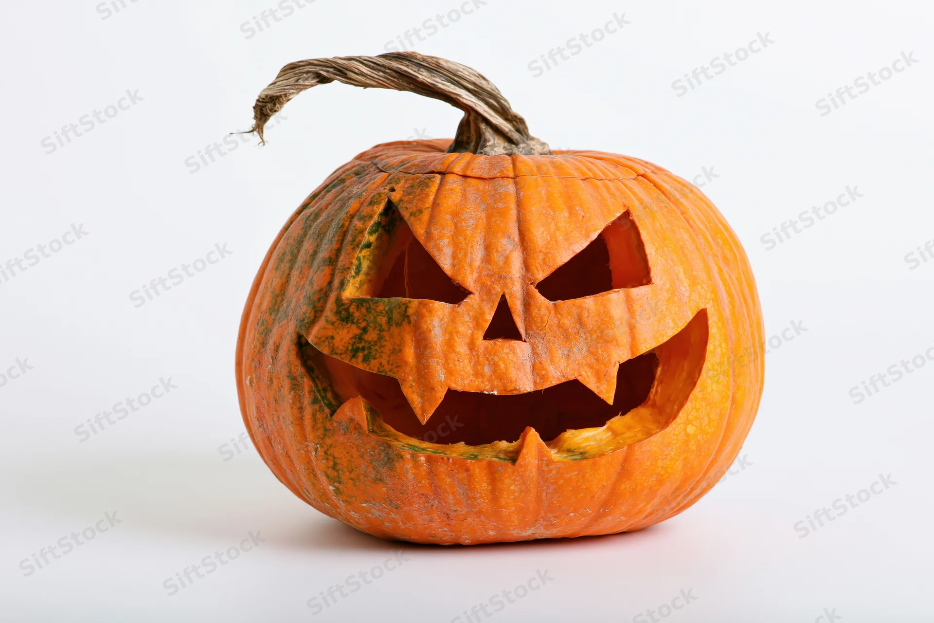 Carved pumpkin with jagged menacing face on white background