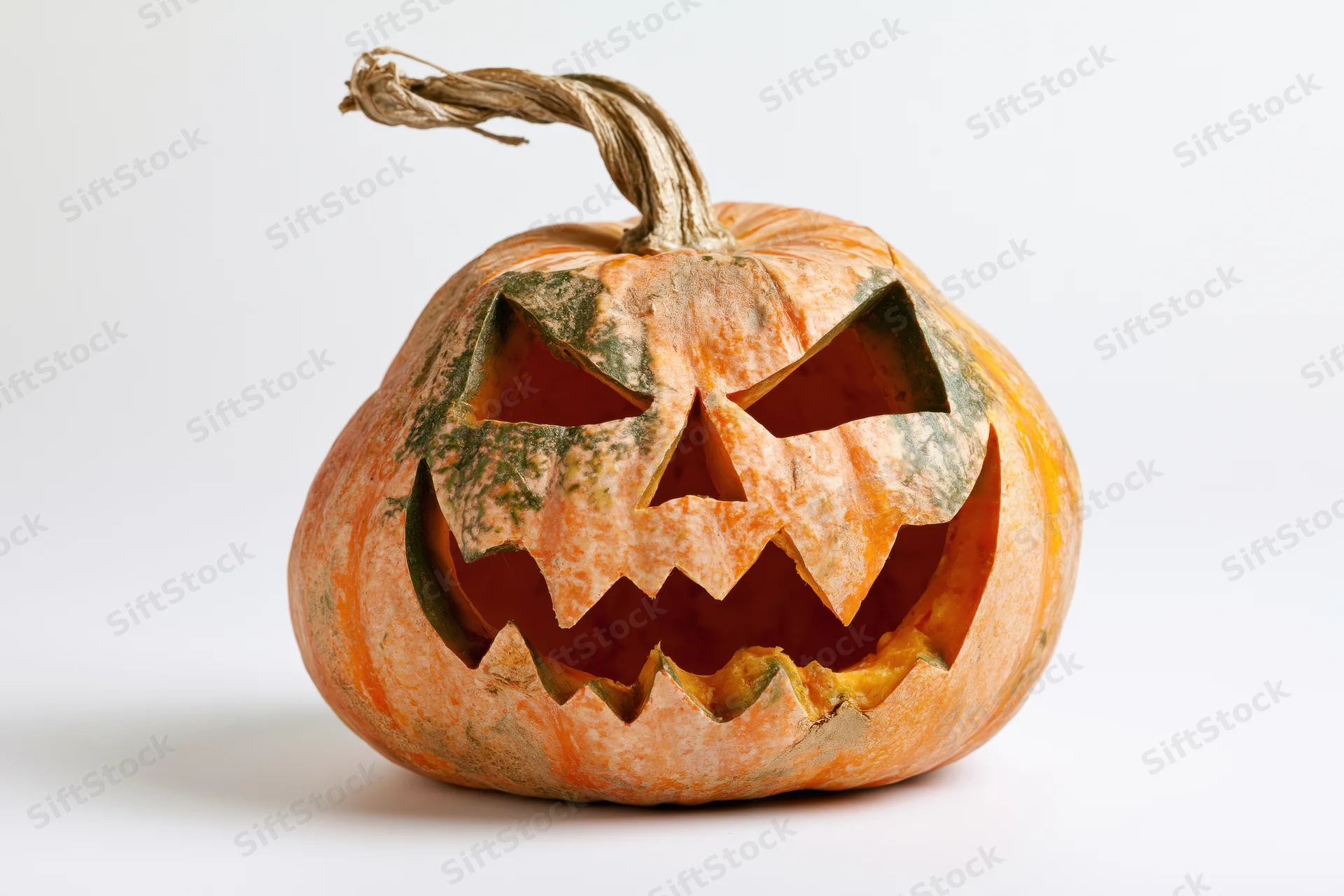 Carved pumpkin with jagged menacing face on white background