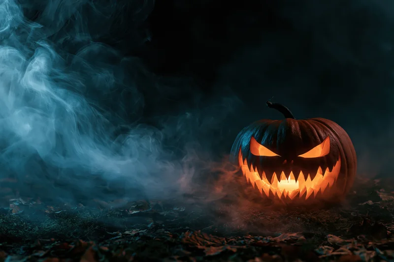 Carved jack-o-lantern with glowing jagged grin in dark smoky forest at night