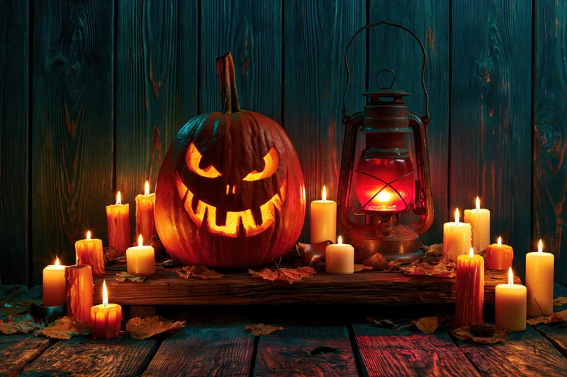 Carved jack-o-lantern with menacing grin and glowing candles on wooden table against dark wood backdrop
