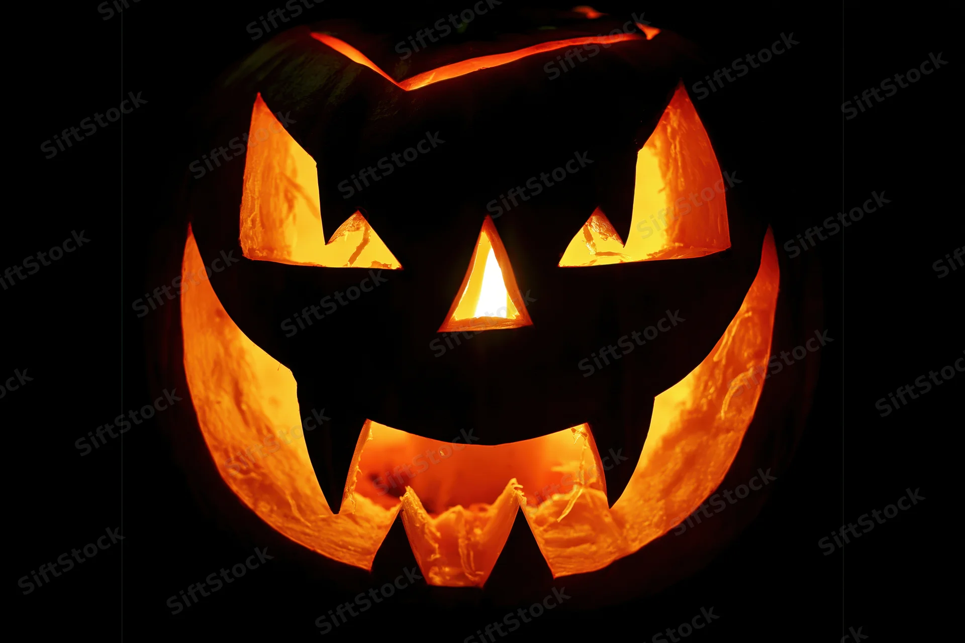 Carved jack-o-lantern glowing with orange light in dark close-up
