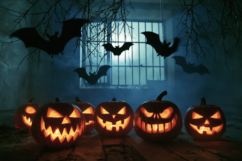 Carved jack-o-lanterns glowing on a rotting wooden floor beneath hanging bat silhouettes and a barred window at night