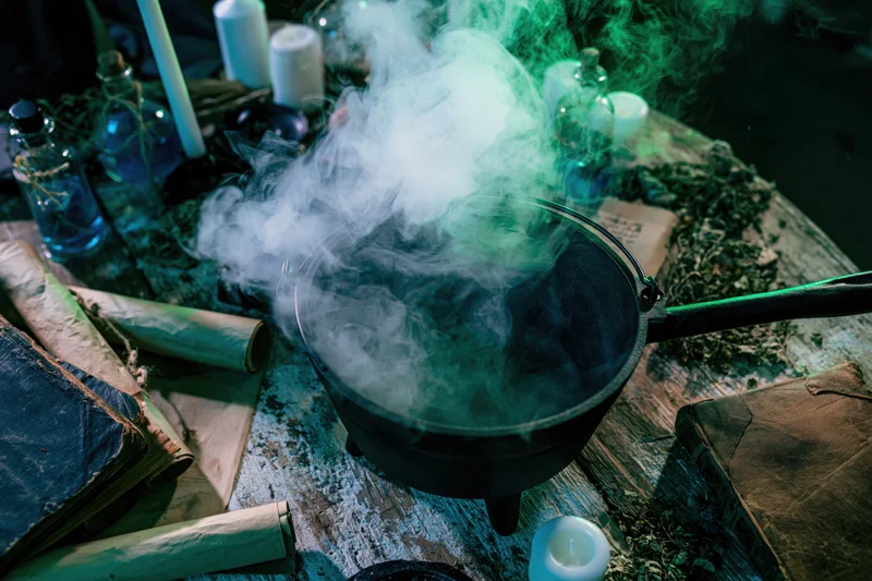 Cast iron cauldron billowing thick white smoke on a wooden table surrounded by mystical objects and candles