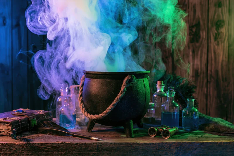 Cast iron cauldron steaming with colorful smoke on rustic wooden table surrounded by potion bottles and grimoire