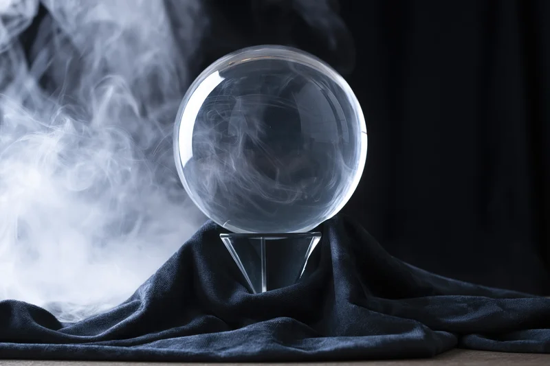 Clear glass crystal ball with swirling smoke on a dark cloth base