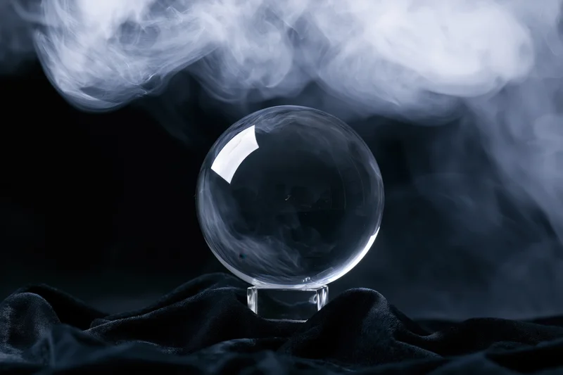 Crystal ball on a crystal base surrounded by smoke on dark velvet fabric