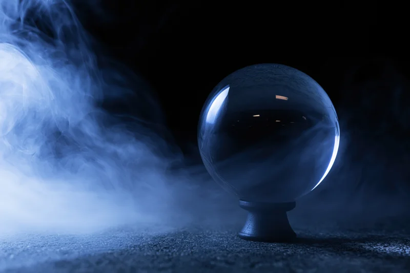 Crystal ball on a dark pedestal surrounded by swirling blue smoke